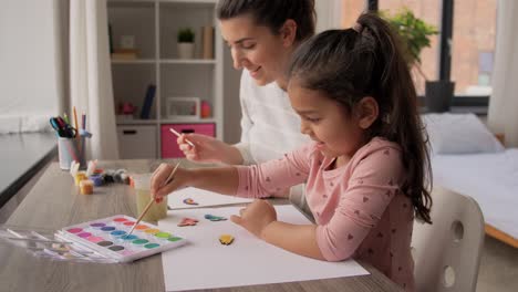 Mother-and-Daughter-Collaborating-on-a-Colorful-Painting-at-Home.Overhead-view-of-a-mother-and-her-young-daughter-working-together-on-a-vibrant-painting,-creating-a-shared-artistic-experience.