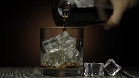 Pouring-whiskey,-cognac-into-glass.-Dark-background.-Pour-of-alcohol-drink