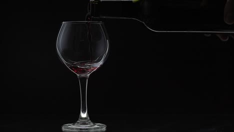 Rose-wine.-Red-wine-pour-in-wine-glass-over-black-background.-Slow-motion