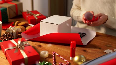 Hände-Verpacken-Weihnachtsgeschenkboxen-Mit-Papier.-Weihnachtsgeschenke-Verpacken.-Weibliche-Hände-Verpacken-Weihnachtsgeschenkboxen-Mit-Papier.-Tischansicht,-POV.