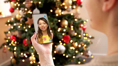 Mujer-Con-Teléfono-Inteligente-Tiene-Una-Videollamada-En-Navidad.-Concepto-De-Navidad,-Tecnología-Y-Vacaciones:-Primer-Plano-De-Una-Mujer-Joven-Con-Un-Teléfono-Inteligente-Que-Tiene-Una-Videollamada-Con-Su-Madre-Mayor-En-Casa