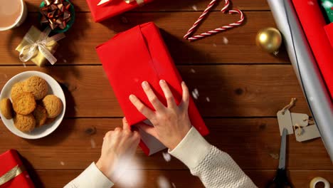 Woman-showing-Christmas-gift-wrapped-in-craft-paper-with-red-bow.-Vertical-video.Woman-showing-Christmas-gift-wrapped-in-craft-paper-with-red-bow.-Smiling-female-is-holding-New-Year-present-box.-Celebrating-Merry-Christmas-or-Happy-New-Year-2025.-Vertical-video