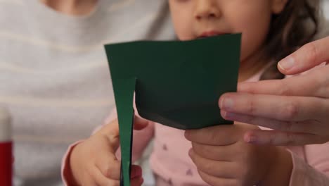 Madre-E-Hija-Cortando-Papel-De-Color-Con-Tijeras.-Concepto-De-Familia,-Arte-Y-Manualidades:-Madre-E-Hija-Cortando-Un-Trozo-De-Papel-De-Color-Verde-Con-Tijeras-En-Casa