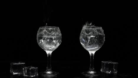 Add-ice-cubes-to-shots-of-vodka-in-glasses.-Black-background.-Alcohol-drink