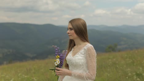 Schöne-Braut-Im-Hochzeitskleid-Aufenthalt-Auf-Den-Bergen-Mit-Blumenstrauß