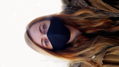 Woman-Wearing-Reusable-Protective-Mask-in-Winter.health,-safety-and-pandemic-concept-–-young-woman-wearing-black-face-protective-reusable-barrier-mask-outdoors-over-snow-in-winter