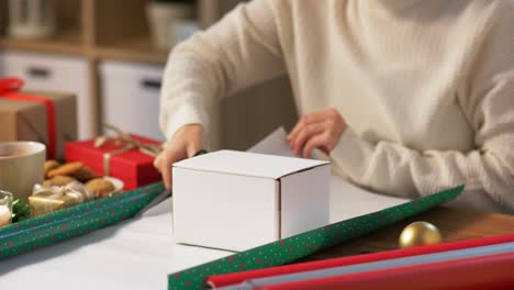 Hände-Verpacken-Weihnachtsgeschenkboxen-Mit-Papier.-Weihnachtsgeschenke-Verpacken.-Weibliche-Hände-Verpacken-Weihnachtsgeschenkboxen-Mit-Papier.-Tischansicht,-POV.