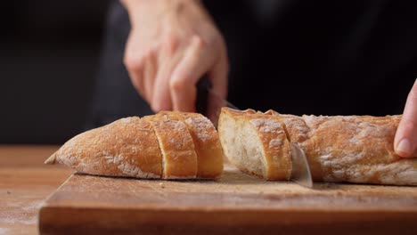 Panadera-Cortando-Pan-Casero-En-La-Panadería.-Concepto-De-Cocina,-Repostería-Y-Personas:-Panadera-Con-Cuchillo-Cortando-Pan-En-Rebanadas-En-La-Panadería-O-La-Cocina