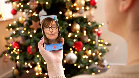 Woman-with-Smartphone-Has-Video-Call-on-Christmas.christmas,-technology-and-holidays-concept-–-close-up-of-young-woman-with-smartphone-having-video-with-senior-mother-call-at-home