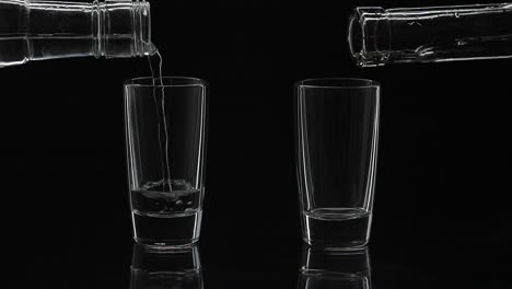 Zwei-Shots-Wodka-Aus-Einer-Flasche-In-Ein-Glas-Gießen.-Schwarzer-Hintergrund