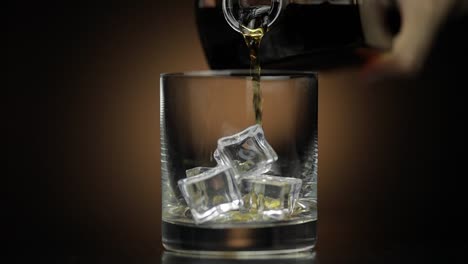 Pouring-whiskey,-cognac-into-glass.-Dark-background.-Pour-of-alcohol-drink