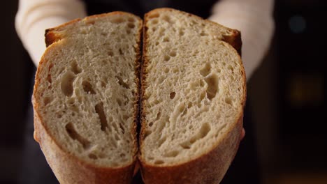 Bäckerin-Zeigt-Selbstgebackenes-Brot-In-Der-Bäckerei.Konzept-Für-Kochen,-Backen-Und-Menschen-–-Bäckerin-Zeigt-In-Der-Bäckerei-Oder-Küche-Einen-In-Zwei-Hälften-Geschnittenen-Laib-Brot