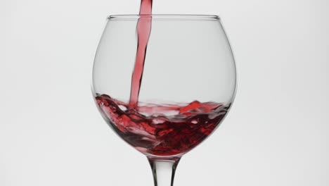 Rose-wine.-Red-wine-pour-in-wine-glass-over-white-background.-Slow-motion