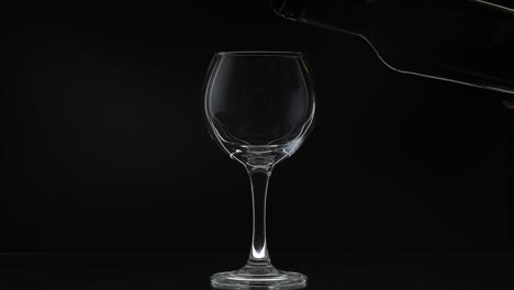 Rose-wine.-Red-wine-pour-in-wine-glass-over-black-background.-Slow-motion