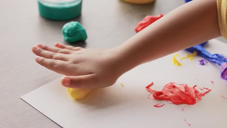 Niña-Pequeña-Haciendo-Rodar-Plastilina-Amarilla-En-Casa.-Concepto-De-Infancia,-Creatividad-Y-Pasatiempo:-Mano-De-Una-Niña-Afroamericana-Haciendo-Rodar-Plastilina-Amarilla-En-Casa