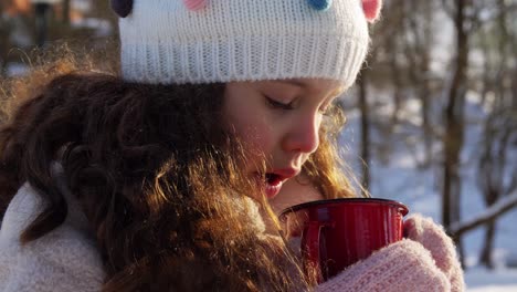 Niña-Con-Una-Taza-De-Té-Caliente-En-El-Parque-De-Invierno.-Concepto-De-Infancia,-Ocio-Y-Temporada:-Niña-Feliz-Con-Una-Taza-De-Té-Caliente-En-El-Parque-De-Invierno-Mientras-Cae-La-Nieve