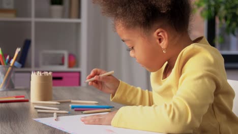 A-happy-little-girl-drawing-and-coloring-with-a-blue-pencil-at-her-desk.A-happy-little-girl-drawing-and-coloring-with-a-blue-pencil-at-her-desk