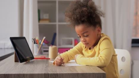 A-happy-little-girl-drawing-and-coloring-with-a-blue-pencil-at-her-desk.A-happy-little-girl-drawing-and-coloring-with-a-blue-pencil-at-her-desk