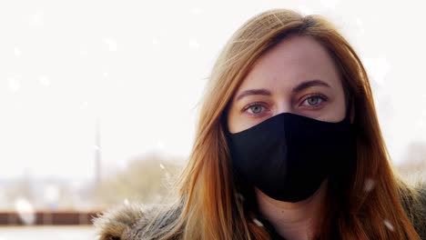 Woman-Wearing-Reusable-Protective-Mask-in-Winter.health,-safety-and-pandemic-concept-–-young-woman-wearing-black-face-protective-reusable-barrier-mask-outdoors-over-snow-in-winter