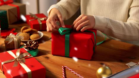 Hände-Packen-Weihnachtsgeschenke-Ein-Und-Binden-Schleife.-Feiertage,-Neujahr-Und-Weihnachtskonzept-–-Hände-Packen-Geschenkboxen-Ein-Und-Binden-Schleife-Zu-Hause-über-Schnee