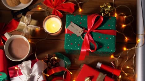 Weihnachtsgeschenke,-Kerzen,-Kaffee-Und-Lichterketten.-Feiertage,-Neujahr-Und-Weihnachtskonzept-–-Geschenkboxen-Mit-Namensschildern,-Kerze,-Heißem-Schokoladengetränk-Im-Becher-Und-Elektrischen-Lichterketten-Auf-Einem-Holztisch-über-Schnee