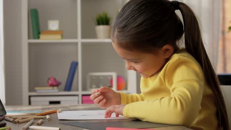 Ein-Glückliches-Kleines-Mädchen,-Das-An-Ihrem-Schreibtisch-Mit-Einem-Blauen-Stift-Zeichnet-Und-Malt.-Ein-Glückliches-Kleines-Mädchen,-Das-An-Ihrem-Schreibtisch-Mit-Einem-Blauen-Stift-Zeichnet-Und-Malt.