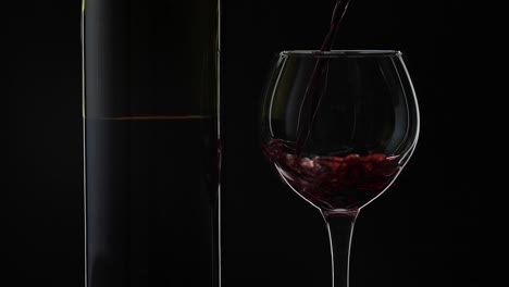 Rose-wine.-Red-wine-pour-in-wine-glass-over-black-background.-Slow-motion