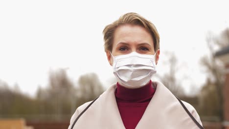 Beautiful-Caucasian-Female-Wearing-Medical-Mask-to-Protect-From-Covid19-Contamination-Young-Woman.Beautiful-Caucasian-female-wearing-medical-mask-to-protect-from-covid-19-contamination.-Young-woman-standing-on-street-and-looking-to-camera.-Virus,-pandemic,-safety-concept.