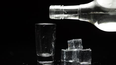 Einen-Schuss-Wodka-In-Ein-Glas-Gießen.-Schwarzer-Hintergrund.-Alkoholisches-Getränk-Einschenken