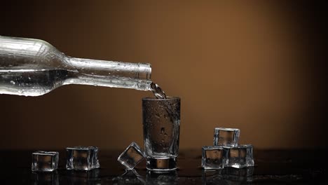 Pouring-up-shot-of-vodka-into-glass.-Dark-brown-background.-Pour-alcohol-drink