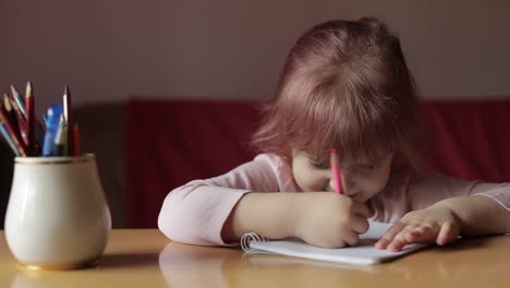 Cute-child-girl-artist-studying-drawing-picture-with-pen-and-pencils-at-home