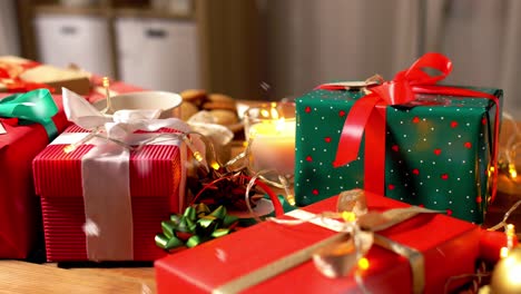 Weihnachtsgeschenke,-Kerzen,-Kaffee-Und-Lichterketten.-Feiertage,-Neujahr-Und-Weihnachtskonzept-–-Geschenkboxen-Mit-Namensschildern,-Kerze,-Heißem-Schokoladengetränk-Im-Becher-Und-Elektrischen-Lichterketten-Auf-Einem-Holztisch-über-Schnee