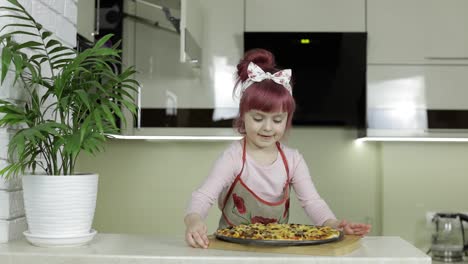 Cooking-pizza.-Little-child-in-apron-with-freshly-baked-hot-pizza-in-kitchen