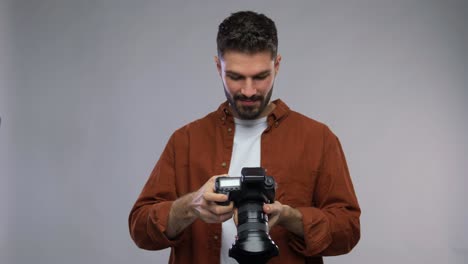 Male-Photographer-Taking-Studio-Portraits-on-Digital-Camera.Back-view-arc-shot-of-professional-male-photographer-taking-studio-portrait-photo-samples-on-dslr-camera-and-looking-at-pictures-on-computer-monitor-while-working-with-assistant-indoors