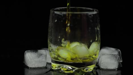 Whiskey-with-ice.-Pouring-whisky-rum-from-the-bottle-on-black-background