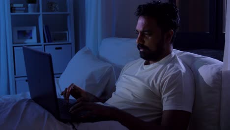 Indian-Man-with-Laptop-in-Bed-at-Home.people,-bedtime-and-rest-concept-–-indian-man-with-chroma-key-green-screen-on-laptop-computer-lying-in-bed-at-home