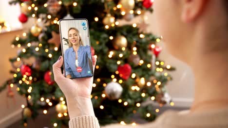 Mujer-Con-Teléfono-Inteligente-Tiene-Una-Videollamada-En-Navidad.-Concepto-De-Navidad,-Tecnología-Y-Vacaciones:-Primer-Plano-De-Una-Mujer-Joven-Con-Un-Teléfono-Inteligente-Que-Tiene-Una-Videollamada-Con-Su-Madre-Mayor-En-Casa