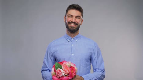 Glücklich-Lächelnder-Junger-Mann-Mit-Einem-Blumenstrauß.Valentinstag,-Gruß--Und-Feiertagskonzept-–-Videoporträt-Eines-Glücklich-Lächelnden-Jungen-Mannes-Mit-Einem-Blumenstrauß-Auf-Grauem-Hintergrund