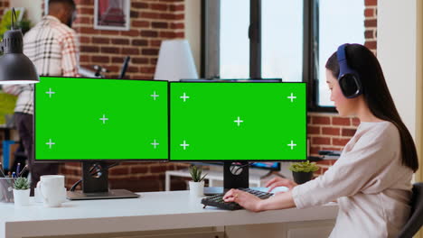 Asian-freelancer-working-on-her-tasks-with-green-screen-on-pc-display