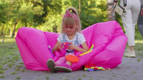 Joyful-girl-playing,-spinning-with-pop-it-sensory-anti-stress-toy-in-park,-stress-anxiety-relief