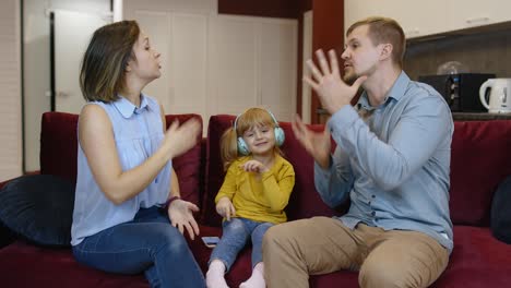 Child-girl-trying-to-be-distracted-and-not-hear-quarrels-between-parents-at-home.-Family-problems