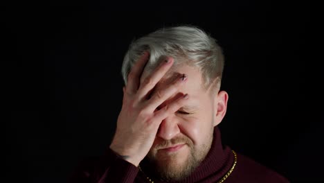 Disappointed-man-doing-face-palm-gesture-on-black-background.-Stressed-guy-covering-face-with-hand