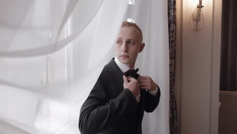 Handsome-stylish-groom-man-wearing-green-jacket-at-home-in-living-room,-slow-motion-indoors-portrait