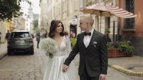 Newlyweds-portrait,-caucasian-groom-bride-walking,-embracing,-hugs-on-city-street,-wedding-couple