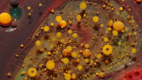 Top-view-movement-of-orange-oil-ink-drops-bubbles,-multicolored-artistic-paint-surface-background