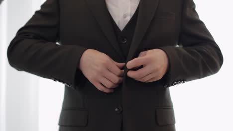 Groom-buttoning-jacket,-man-in-suit-fastens-buttons-on-his-jacket-preparing-to-go-out