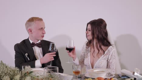 Caucasian-groom-and-bride-drinking-champagne-or-wine-from-glasses,-wedding-ceremony-in-restaurant