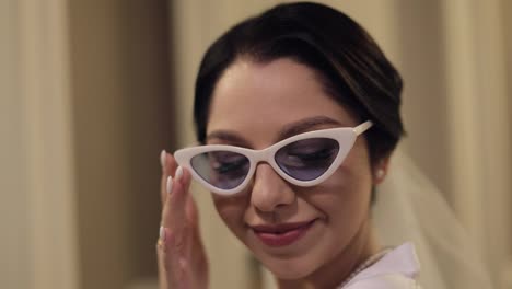 Closeup-of-beautiful-stylish-bride-girl-in-sunglasses-looking-at-camera-and-smiling,-wedding-morning