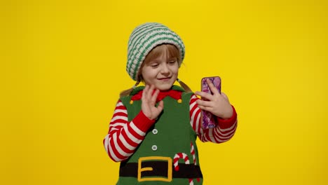 Kid-child-girl-in-Christmas-elf-Santa-Claus-helper-costume-making-a-video-call-on-mobile-phone