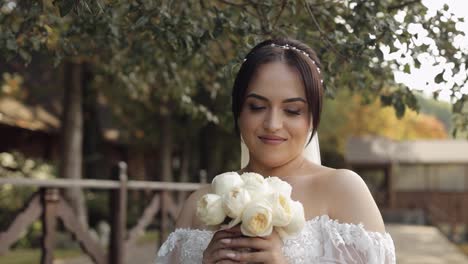 Schöne-Stilvolle-Braut-Im-Weißen-Brautkleid-Und-Schleier-Mit-Brautstrauß-In-Den-Händen-Im-Park